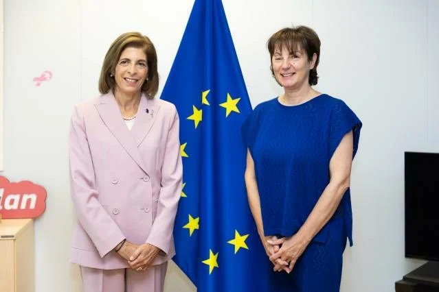 Commissioner Kyriakides and Olga Kikou standing side by side before the EU flag